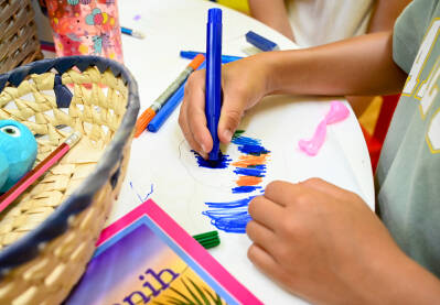 Dječak crta na bloku. Dječak koji crta šarenim flomasterima. Djeca crtaju u bilježnici na stolu kod kuće. Obrazovanje djece.