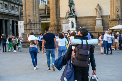 Firenca, Italija: Turist s ruksakom istražuje grad. Putnik sa ruksakom na trgu.