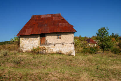 Stara kamena kuća u prirodi. Tradicionalna porodična kuća u planini. Zahrđali limeni krov na napuštenoj kući u selu.