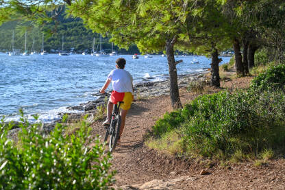 Momak vozi bicikl stazom pored mora. Biciklista na biciklu u prirodi.
