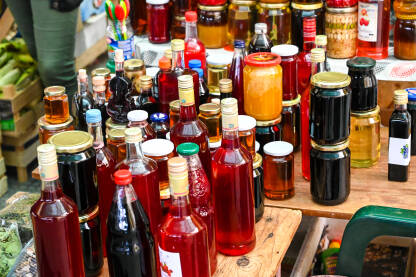 Domaći proizvodi na prodaju na pijaci. Tegle i flaše. Sirup, sok, džem, pekmez, med, čaj.