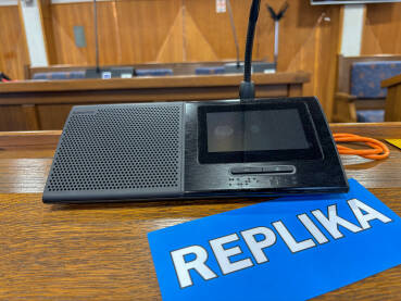 Sjednica u skupštini. Natpis REPLIKA pored poslaničkog mikrofona.