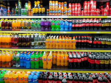 Osvježavajuće piće u frižideru u supermarketu. Boce i limenke. Coca Cola, Fanta, Sprite.