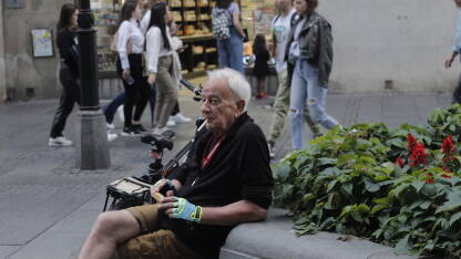 Stariji čovjek odmara na ulici od vožnje bicikla i puši cigaru.