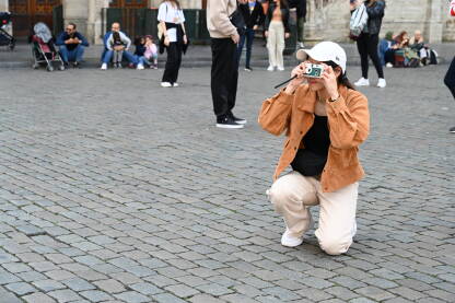 Žena s fotoaparatom na trgu. Fotografkinja. Turisti fotografiraju znamenitost na glavnom trgu. Žena s fotoaparatom.