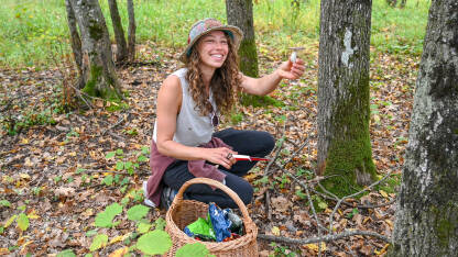 Djevojka bere gljive. Žena s košaricom bere gljive u šumi.