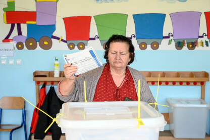 Žena na izborima. Glasčki listić i glasačka kutija. Birači na dan izbora. Ljudi izlaze na izbore. Predsjednički i parlamentarni izbori.