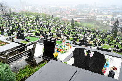 Pravoslavno groblje. Grobovi na groblju tokom kišnog dana. Mramorni spomenici na groblju.