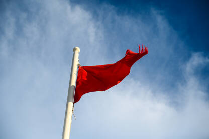 Crvena zastava na plaži kao upozorenje na veliku opasnost ili jake struje.