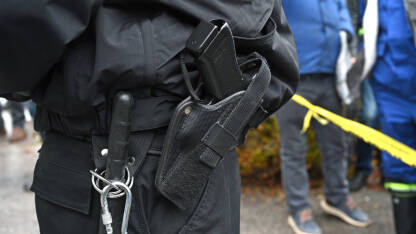 Pištolj na pojasu policajca na protestu. Pištolj na pojasu policajca na protestu. Pištolj u futroli pripadnika specijalnih policijskih snaga. Pištolj i palica policajca.