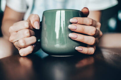 Djevojka drži šolju kafe u ruci.