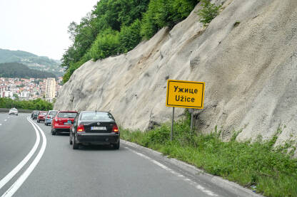 Užice, Srbija. Saobraćajni znak na ulazu u grad. Žuta tabla sa natpisom grada Užica na ćirilici i latinici.