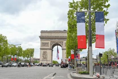 Pariz, Francuska: Slavoluk pobjede s francuskim zastavama ispred. Turisti posjećuju popularnu turističku atrakciju i historijski spomenik u Parizu.