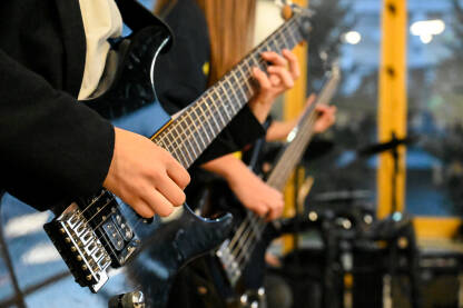 Mladi gitaristi sviraju električnu gitaru i bas gitaru na rock koncertu. Muzičar svira gitaru sa bendom na bini  na muzičkom festivalu.