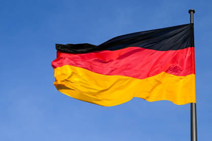 Njemačka zastava se vijori na vjetru na jarbolu. Crna, crvena i žuta boja na njemačkoj zastavi ispred Bundestaga. Simbol njemačkog naroda.