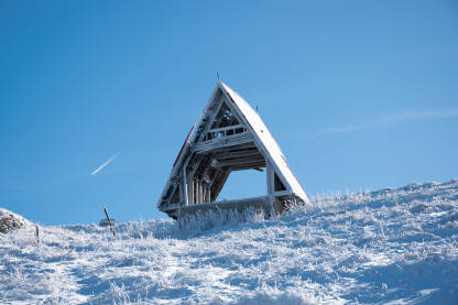 Drvena kuća na vrhovima planine tokom zime.