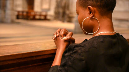 Kršćanka se moli Bogu u katedrali. Katolkinja moli prekriženih ruku.