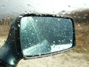 Krupni plan retrovizora automobila mokrog od kiše.