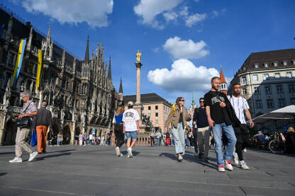 München, Bavarska, Njemačka: Ljudi šetaju na trgu. München, Bavarska, Njemačka: Ljudi šetaju glavnim trgom u centru grada. Marienplatz. Zgrade stare i nove Gradske vijećnice.