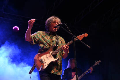 Hrvatski rok muzičar Jurica Pađen nastupa uživo na pozornici s gitarom. Poznati rok gitarista Jurica Pađen svira koncert pod svjetlima pozornice.
