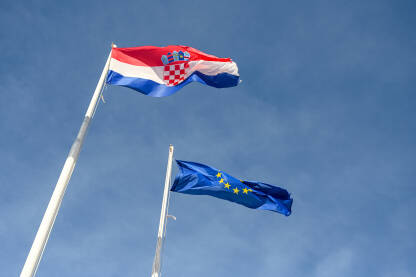 Zastave Hrvatske i EU vijori se na vjetru. Zastave Hrvatske i Europske unije na stupu.