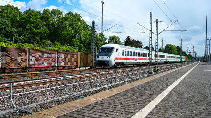Putnički voz prolazi kroz željezničku stanicu. Željeznički prijevoz. Moderni vlak u Njemačkoj.