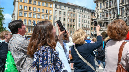 Ljudi fotografišu i snimaju pametnim telefonima u centru grada. Turisti sa mobilnim telefonima u rukama.