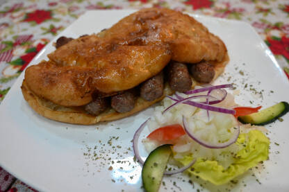 Ćevapi ili ćevapčići. Tradicionalno mesno jelo na Balkanu. Meso pripremljeno na roštilju i servirano uz somun i luk. Popularna hrana.