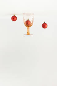 Vintage čaša za piće i crvene Božićne ukrasne kuglice okrenute naopako.