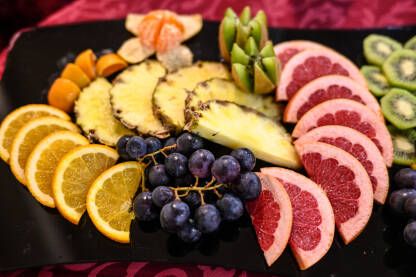Različito voće u zdjeli. Narandža, ananas, kivi, grožđe, grejp. Kriške svježeg voća.
