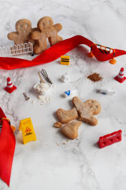 Slomljen keks u obliku čovjeka sa sastojcima za pripremu i znakovima nezgode na putu.