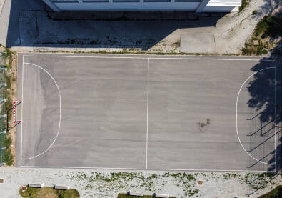 Asfaltirani fudbalski stadion, snimak dronom. Igralište za mali fudbal ispred škole.