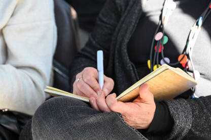 Žena piše u bilježnicu tokom predavanja. Djevojka piše u notes. Žena piše u bilježnicu tokom predavanja. Obrazovanje.