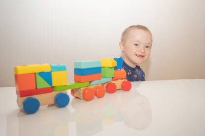 Slatki dječak sa Down sindromom se smije dok se igra sa svojim vozićem