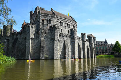 Gent, Belgija: Dvorac uz riječni kanal u centru grada. Utvrđene kule i zidine na srednjovjekovnom utvrđenju. Turisti na brodicama.