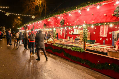 Grupa ljudi na trgu u središtu grada noću. Božićni sajam.