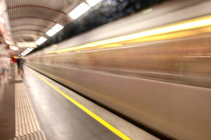 Zamućena fotografija metro voza koji se brzo kreće kroz stanicu. Javni prijevoz.
