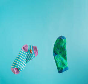 Dva dječija čarapića lebde ispred tirkizne pozadine sa preznim prostorom iznad. 21. mart, koncept.
