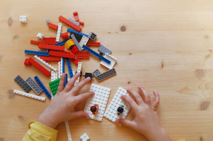 Dječije ruke sa lego kockicama na stolu.