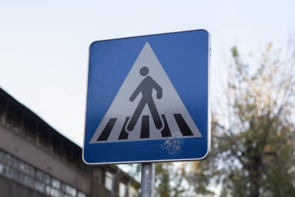 Saobraćajni znak koji označava lokaciju pješačkog prelaza na cesti.