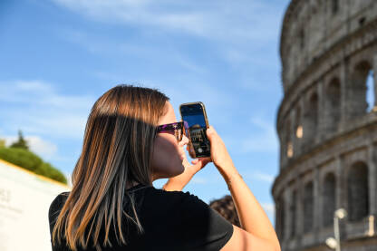 Djevojka mobilnim telefonom fotografiše Coloseum u Rimu. Djevojka mobilnim telefonom fotografiše Coloseum u Rimu. Turisti u gradu.
