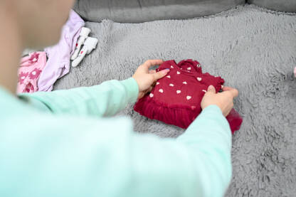 Mama slaže dječju odjeću. Majka slaže bebinu robu.