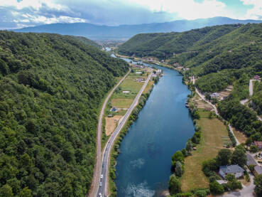 Rijeka teče u dolini između brda, snimci dronom. Rijeka u Bosni i Hercegovini.