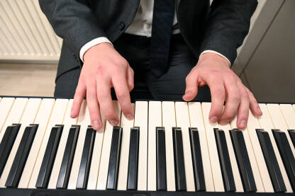 Muškarac svira klavir. Pijanist svira na instrumentu kod kuće. Muzički instrumenti. Električna klavijatura.