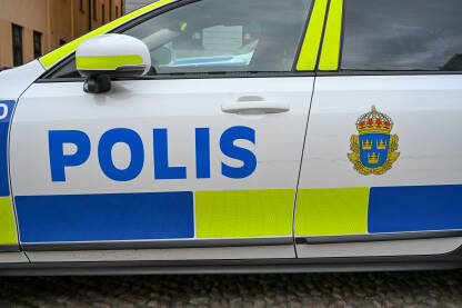 Patrolno vozilo švedske policije s natpisom "POLIS" i  grbom Švedske. Označeno vozilo organa reda švedske policije parkirano na otvorenom.