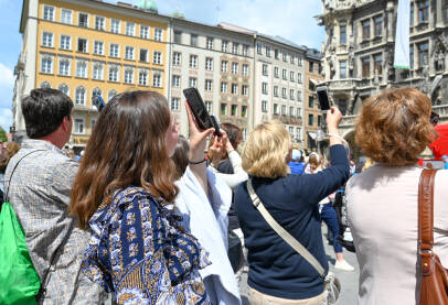 Ljudi fotografišu i snimaju mobilnim telefonima u centru grada. Turisti sa mobilnim telefonima u rukama.