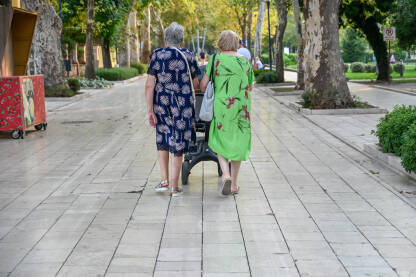Dvije starije žene guraju dječja kolica. Gospođe u šetnji gradom.