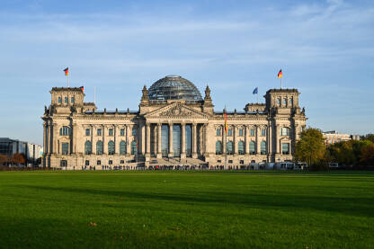 Berlin, zgrada njemačkog parlamenta. Zastave se vijore na jarbolu ispred zgrade Reichstaga u Berlinu, Njemačka. Njemački Bundestag.