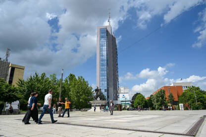 Priština, Kosovo: Grupa ljudi šeta na trgu u centru grada. Zgrada Vlade Kosova.