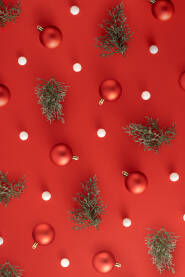 Božićna, novogodišnja pozadina s kuglicama i grančicama bora na crvenoj podlozi.